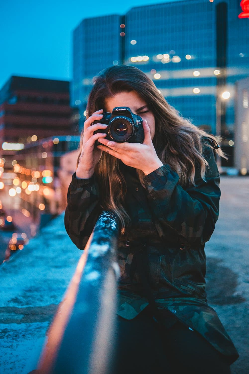 A photographer framing a shot through her camera at blue hour in the city